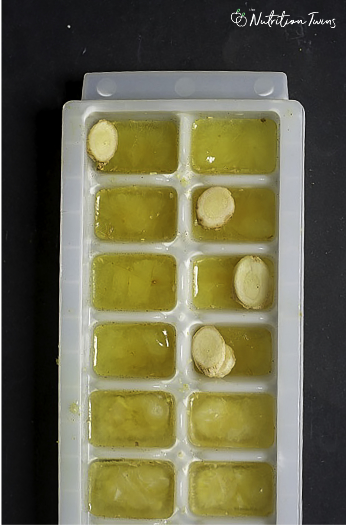 Ginger turmeric ice cubes in tray with ginger slices